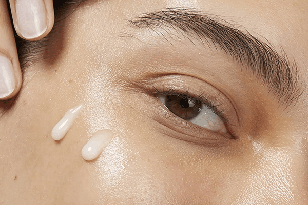 model applying two drops of cream on her cheeks
