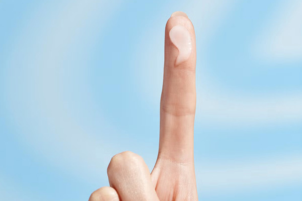 an image of a finger holding a drop of hyaluronic acid. shot in a studio of blue background with white swirls.