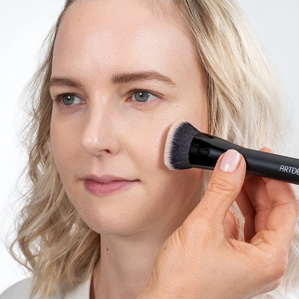 Applying camouflage cream with a contouring brush