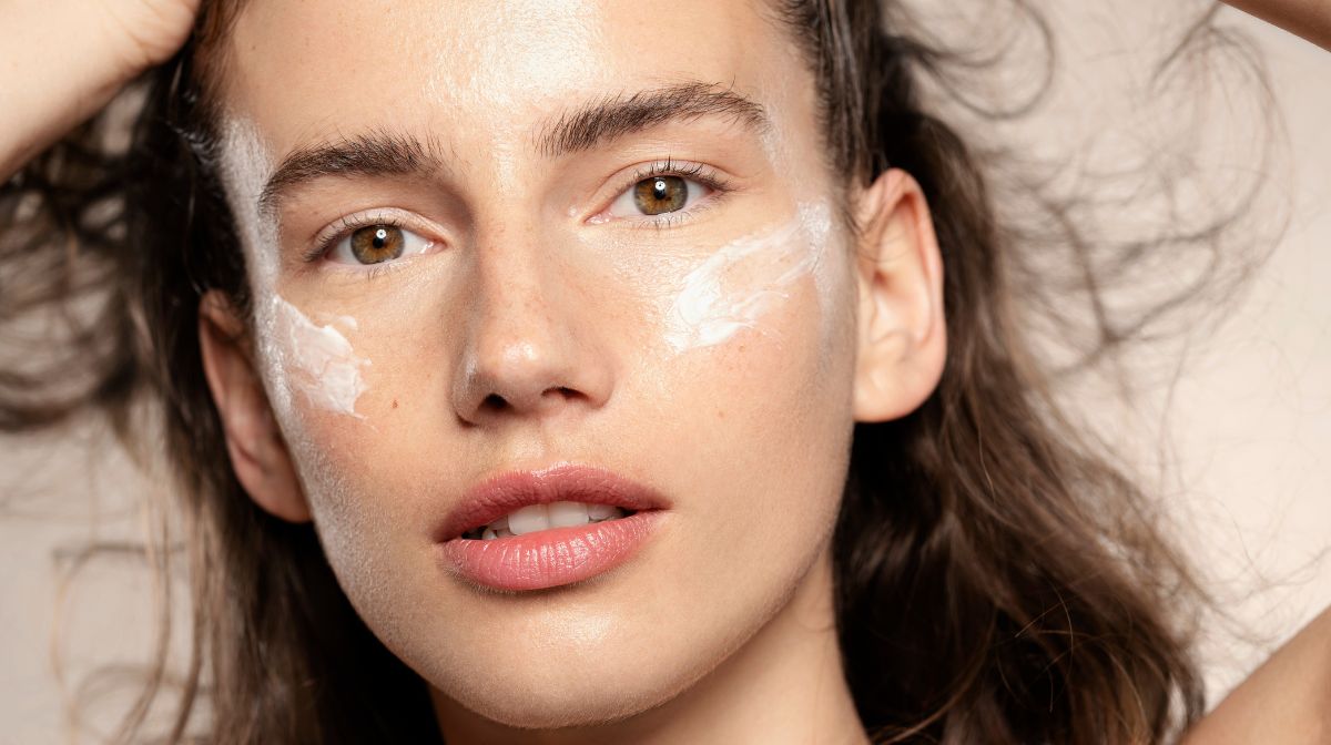 Young woman applies moisturiser to her face | Skin Virtue