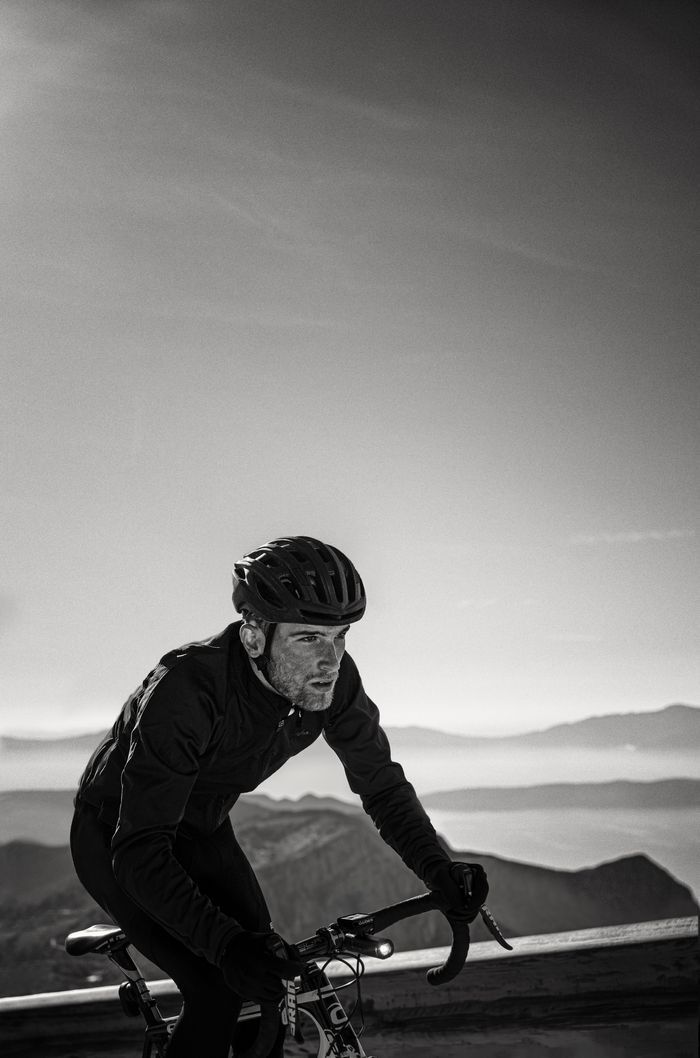 black and white image of man riding a bike