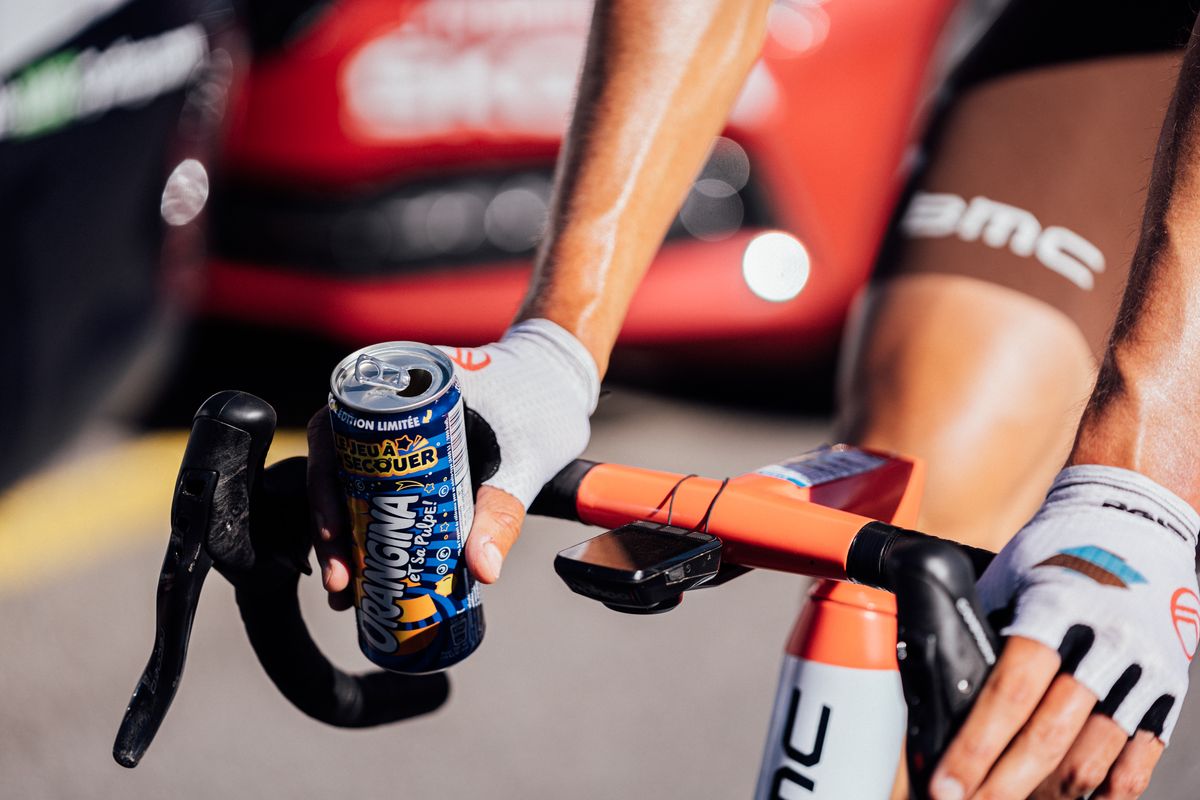 A pro cyclists holding a can of drink