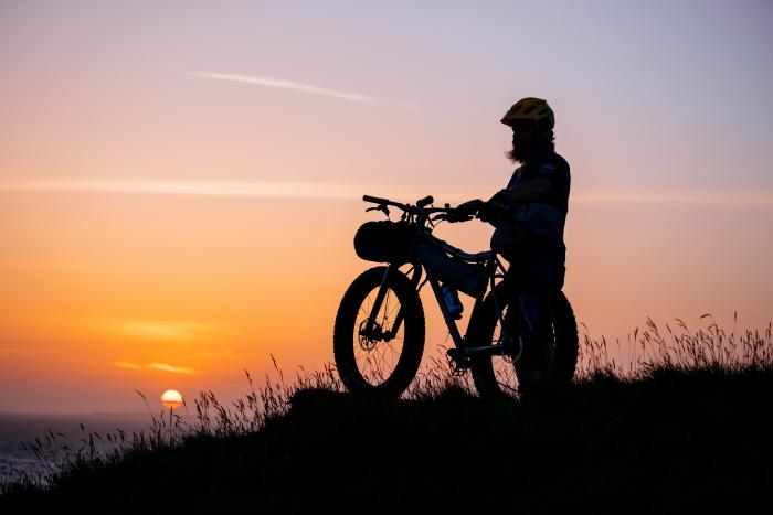 Silhouette of a bikepacking cyclist with sunset in the background