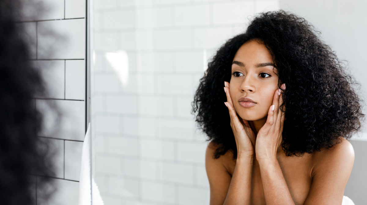 woman touching her face in the mirror.