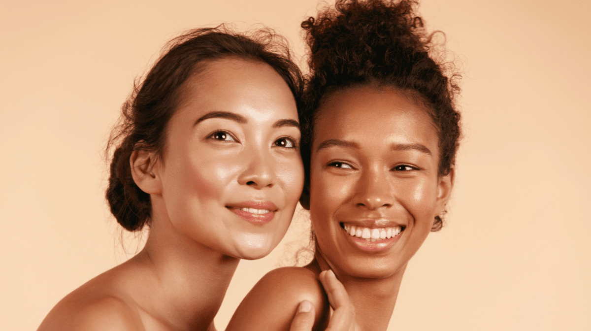 Two woman laughing with glowing skin.