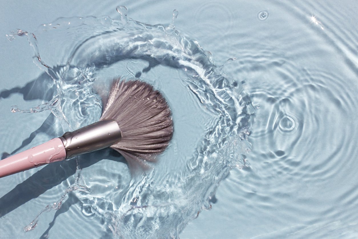 Makeup brush being dipped in water before being cleaned