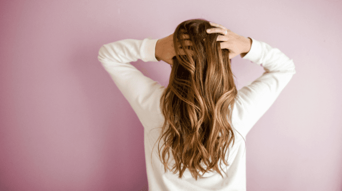 woman running hands through her healthy hair after learning how to repair it.