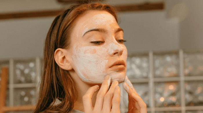 Woman applying a salicylic acid face mask to her face.
