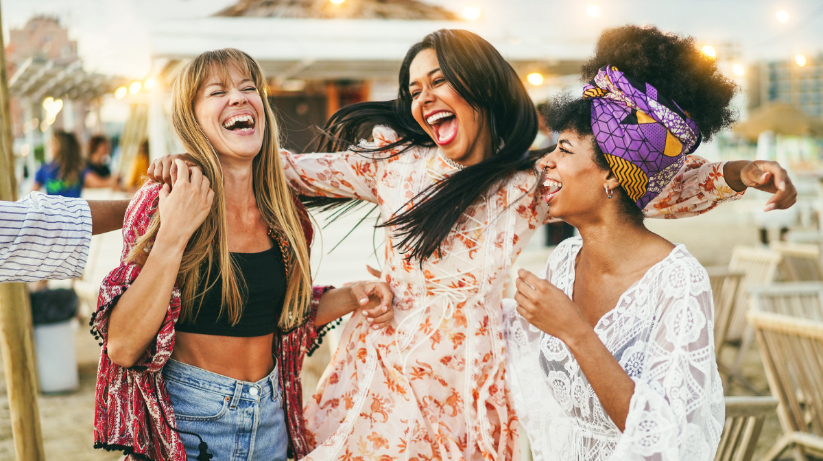 Three women laughing together at a festival.