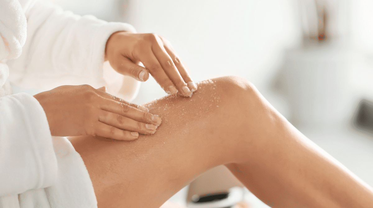 Woman applying a body scrub to her legs.