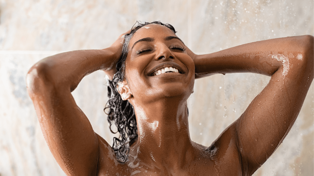 Woman washing her hair in the shower with a shampoo for dry hair.