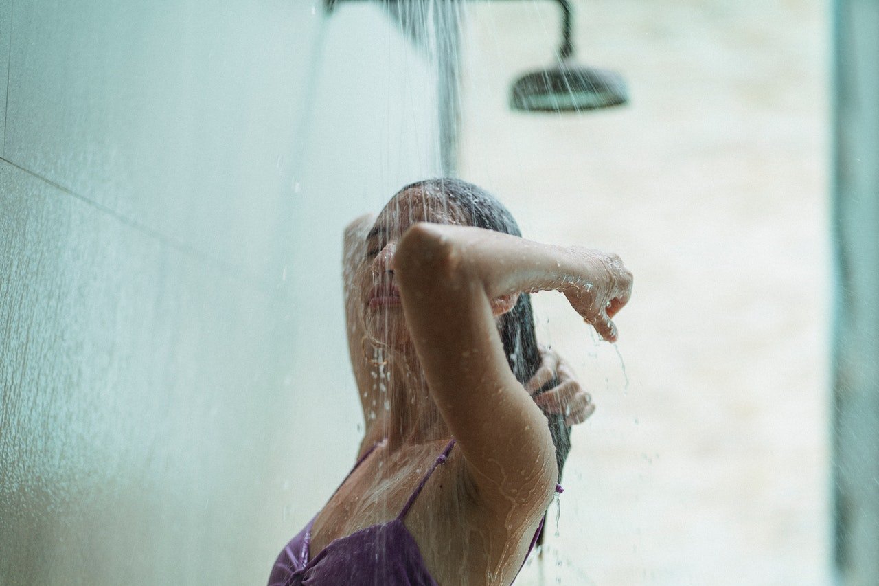 Frau in der Dusche wäscht ihre Haare