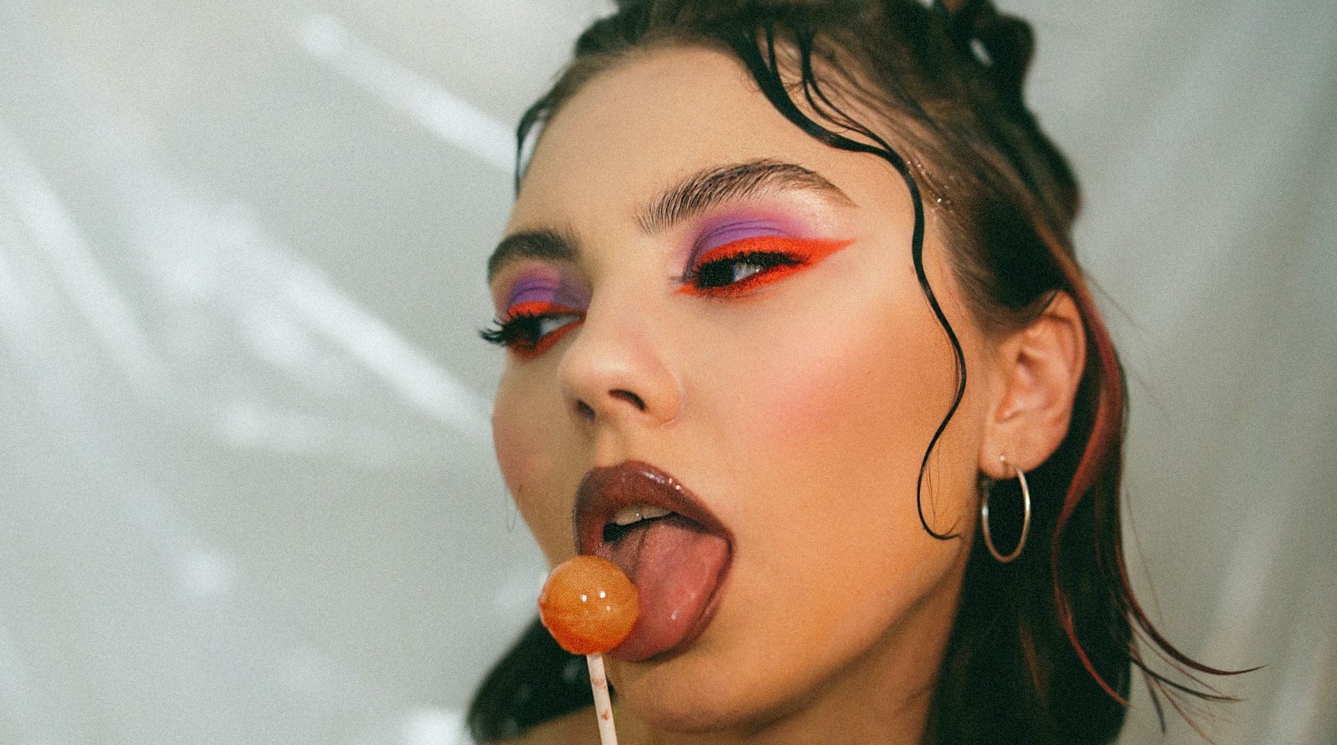 woman with lollypop and colourful eye makeup