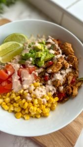 Chicken burrito bowl with rice, corn, chicken, lime, tomatoes and dressing