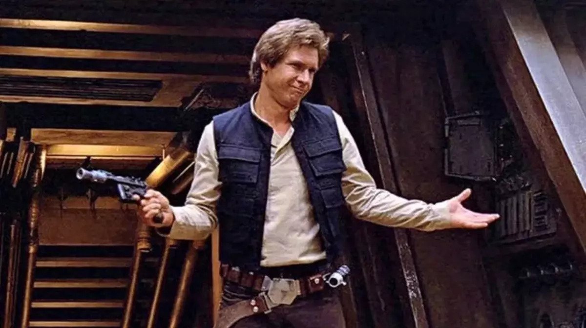 Han Solo smirking whilst shrugging his shoulders with a gun in his right hand