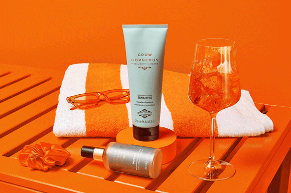 Orange sun lounger and orange cocktail next to the top rated beauty products: GG Sensitive Shampoo and Defence Spray.