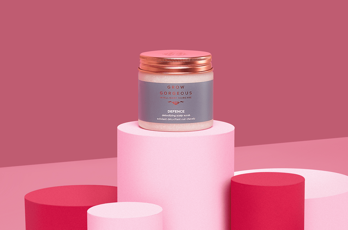 Grow Gorgeous Defence hair scrub containing niacinamide placed in front of a pink background.