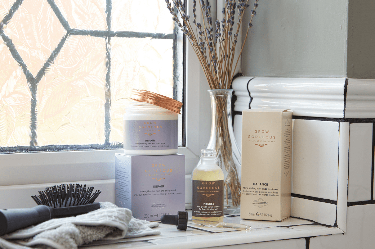 Four grow gorgeous products next to hair brush and flowers