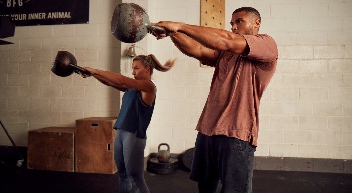 man and woman performing kettlebell swings in raw collection