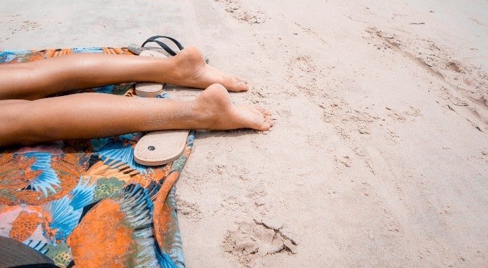 Persona tumbada en la playa Dicas para dormir melhor quando está muito calor