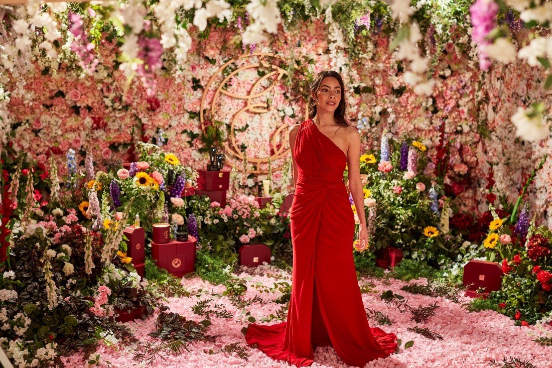 Woman in red dress standing in magical Christmas Festive scene with luxuriously wrapped Christmas Presents in background