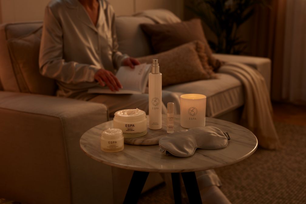 Woman on sofa writing wellness new years resolution in her diary. On display are all her ESPA products she needs to achieve her goals.