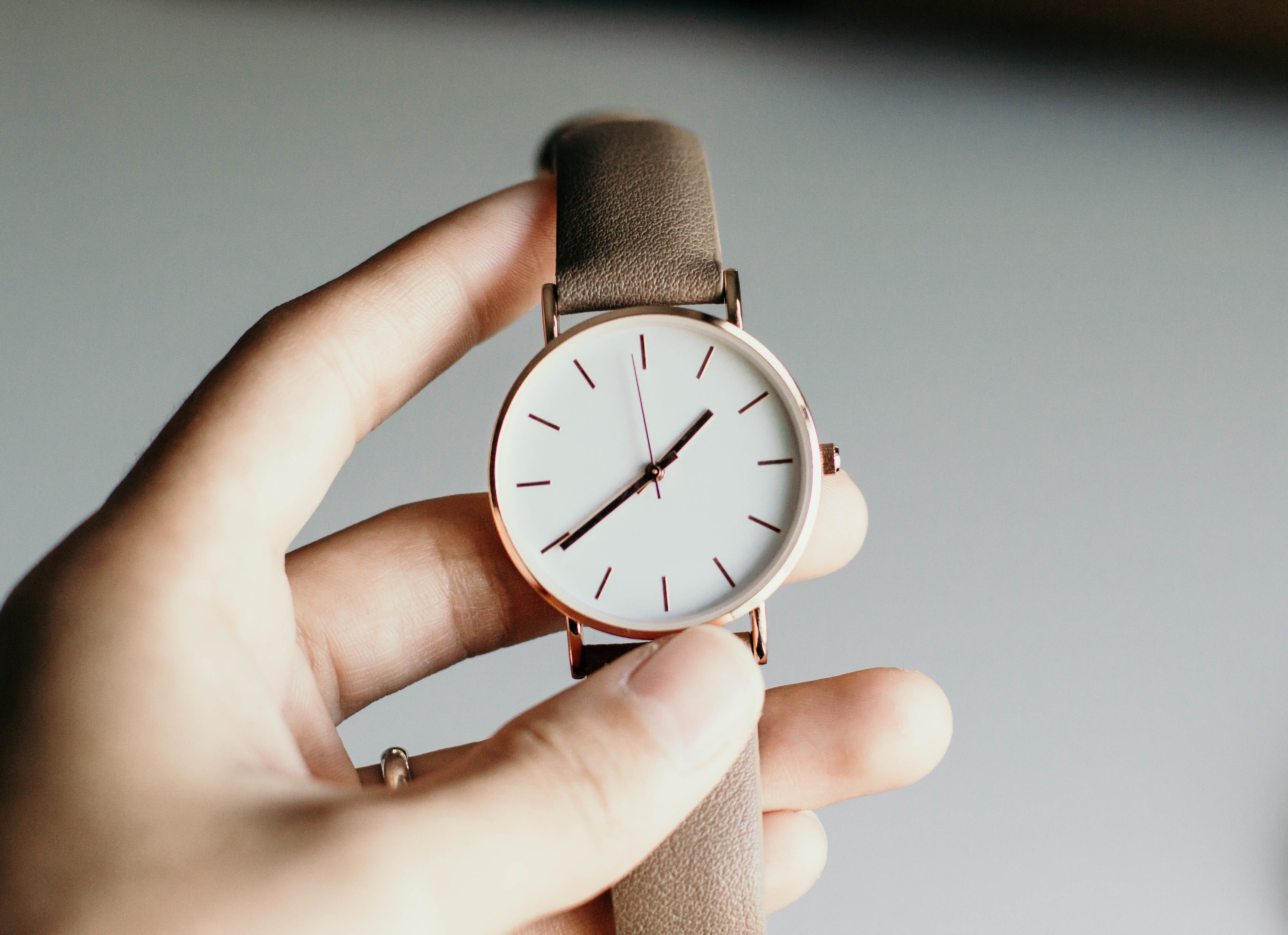 hand holding watch reading the time 1.39pm. 