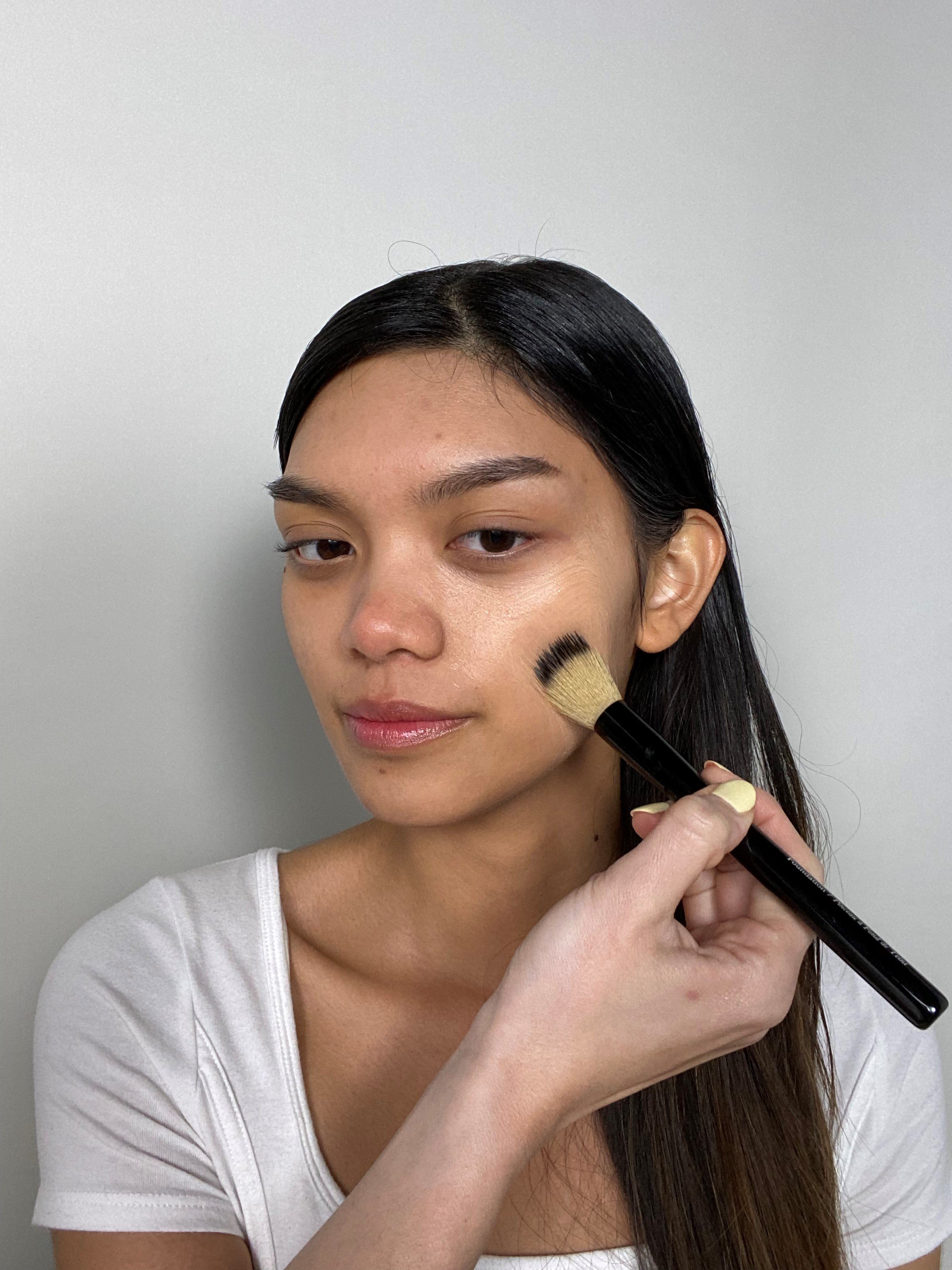 girl applying foundation onto face