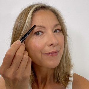 woman using pencil to fill in sparse eyebrow
