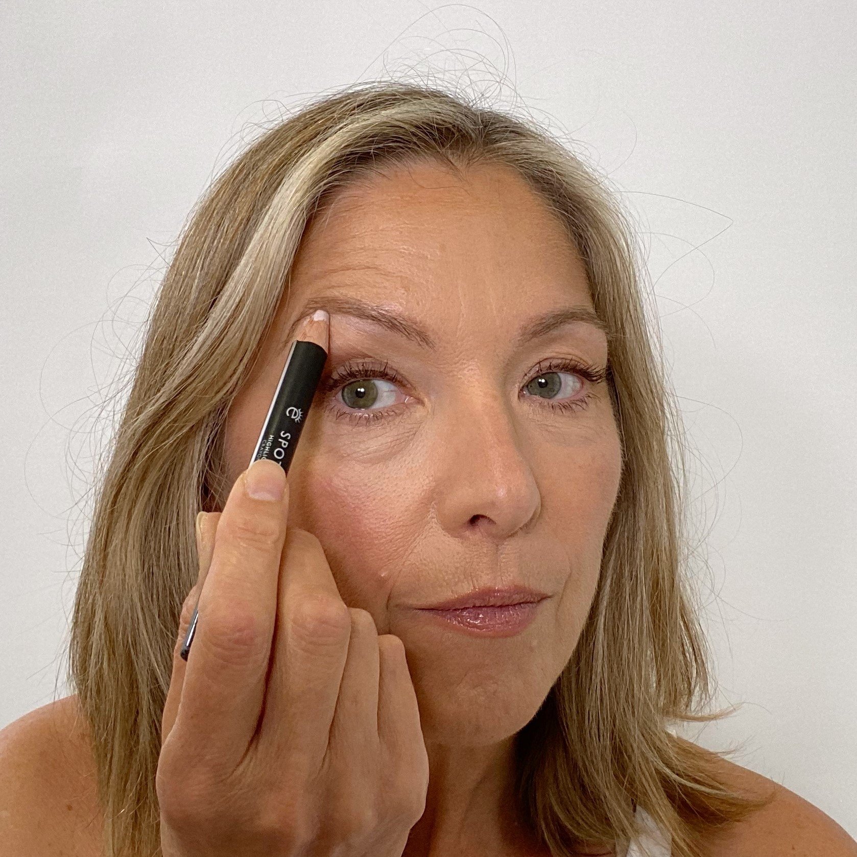 woman using highlighter under the brow arch
