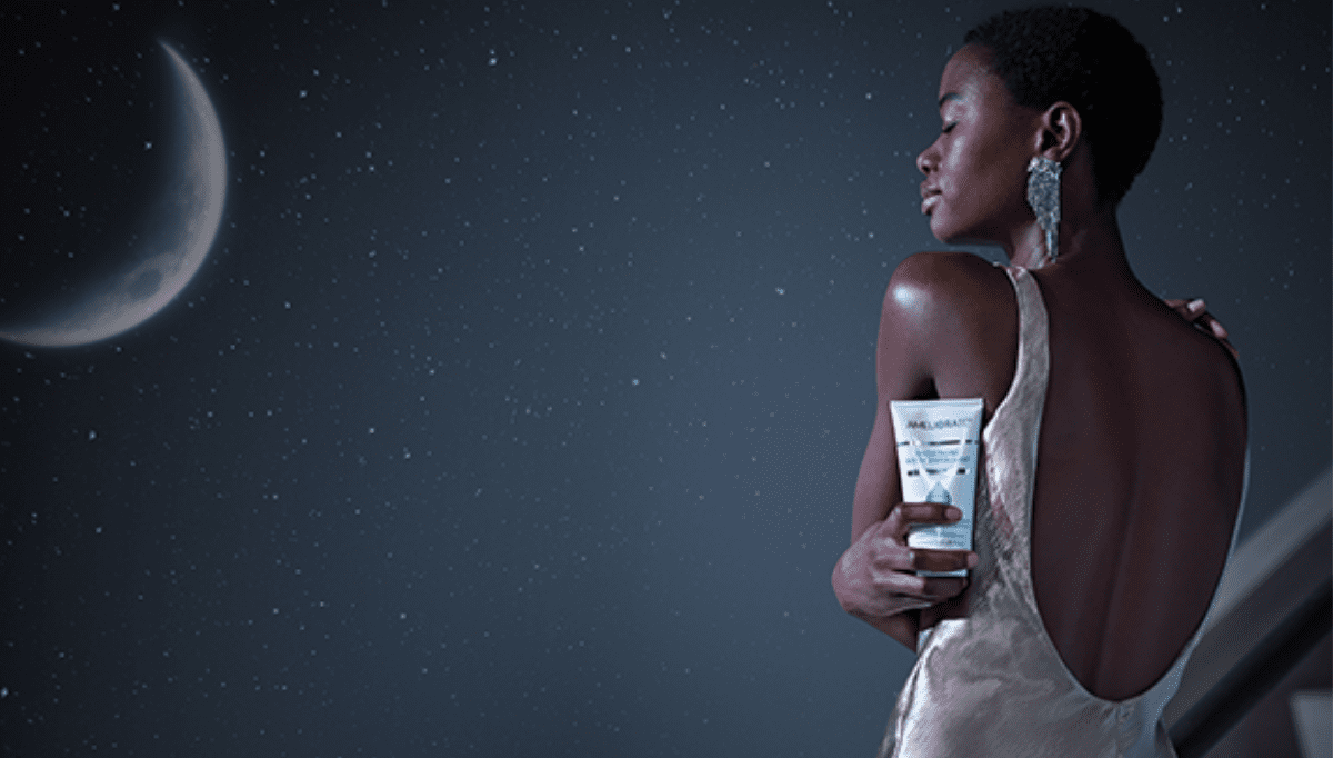 woman holding smoothing body exfoliant with night time background