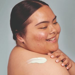 woman rubbing cream onto back