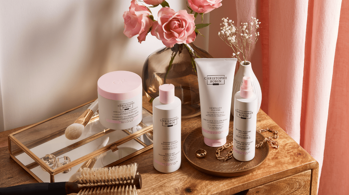 Christophe Robin pink and white Volume hair products on a dressing table with flowers