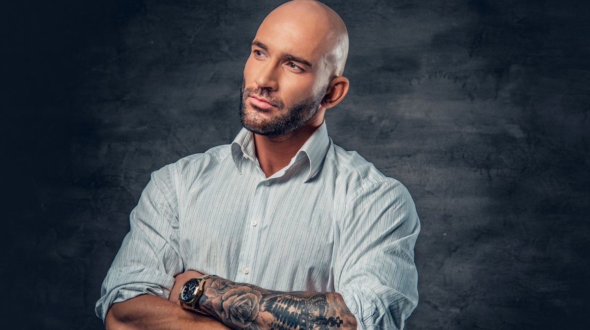 smartly dressed man with tattoos and a shaved head