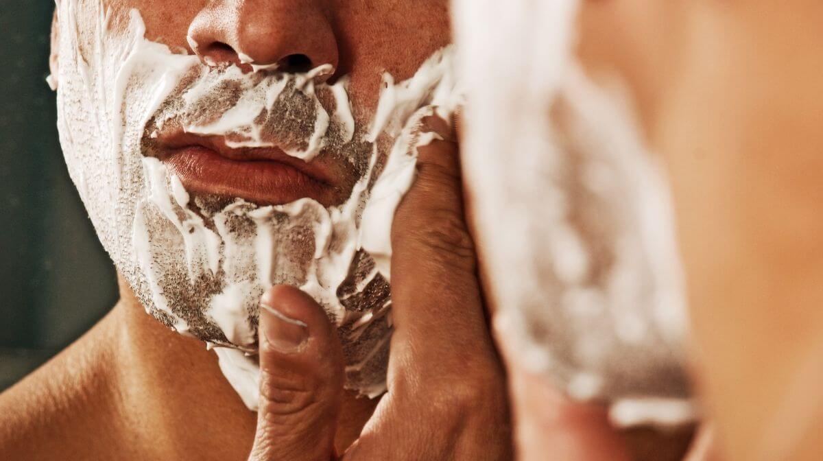 man using shaving cream to prevent dry skin after shaving
