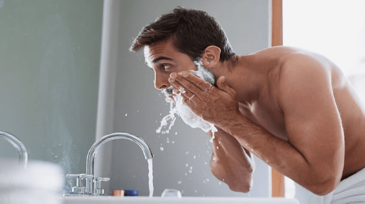 man washing away shaving foam
