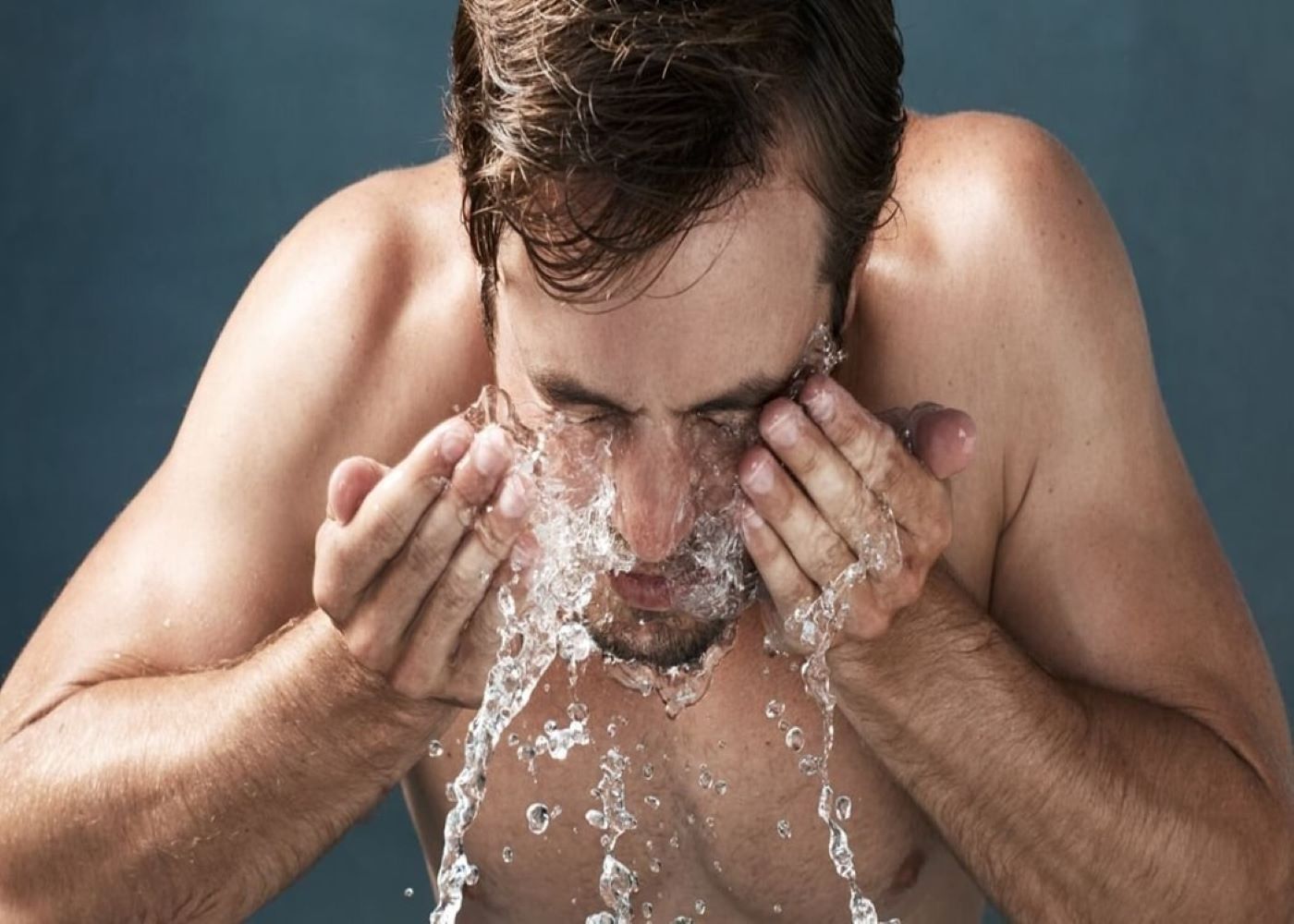 man splashing his face with water