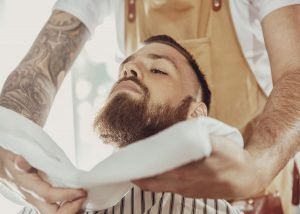 bearded man enjoying a hot towel shave