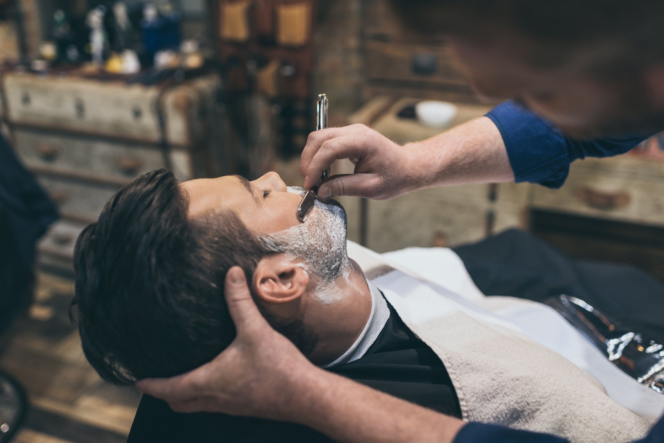 barber doing against the grain shaving with straight edge razor 