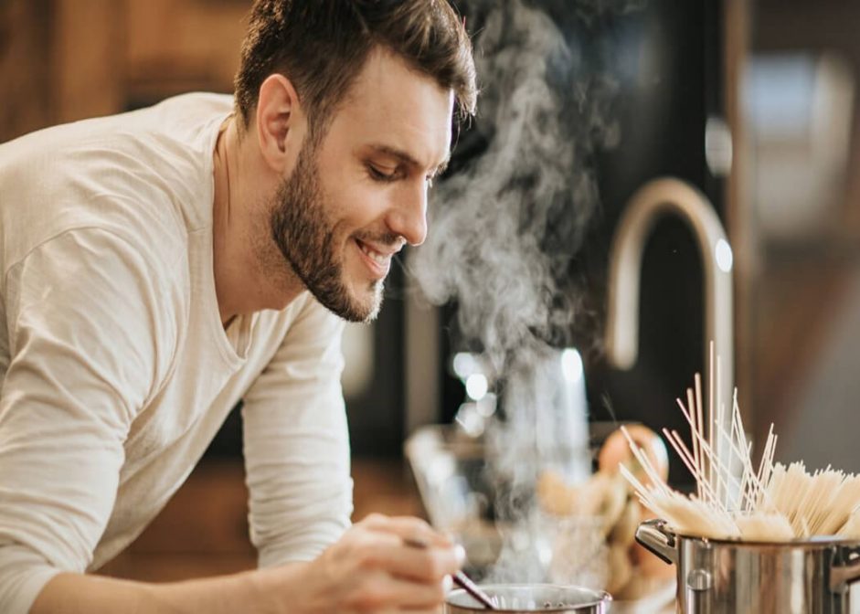 male university student cooking pasta for his flatmates