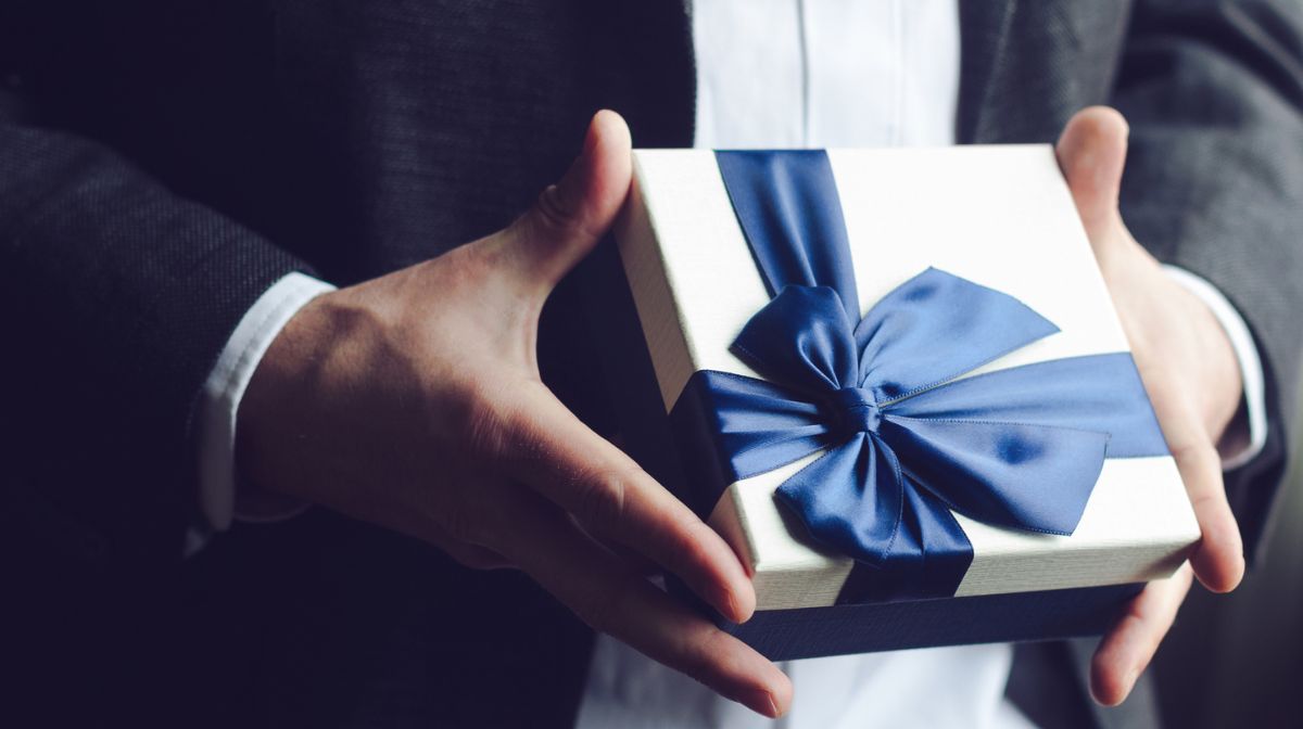 A man holds one of the best gifts for men in a ribbon-wrapped box | Gillette UK