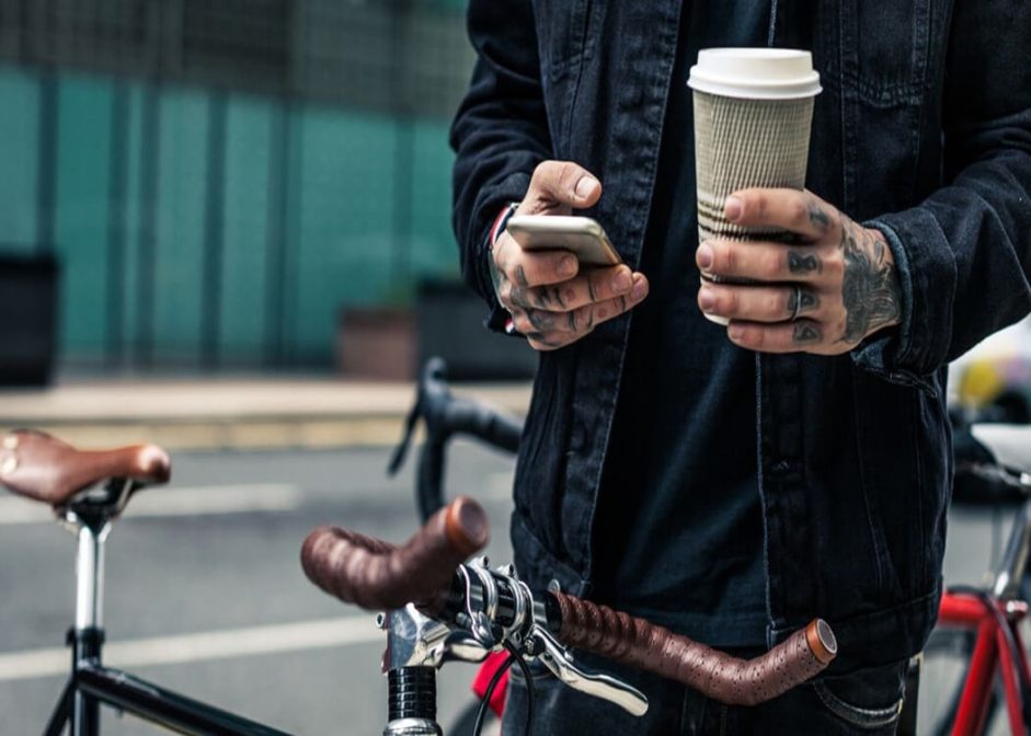 man cycling while using a recycled coffee cup as part of a green lifestyle