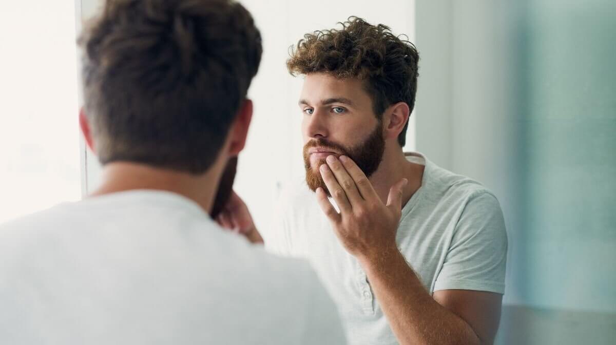 man exfoliating the skin around his beard