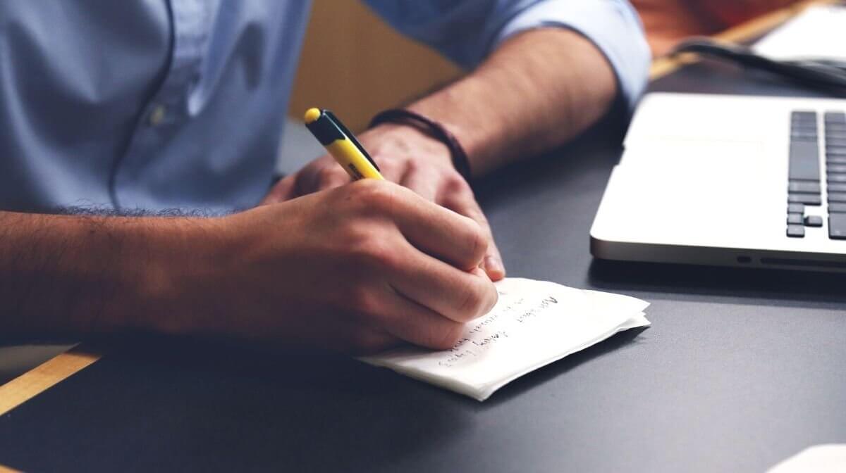 man writing a to-do list to keep him on track