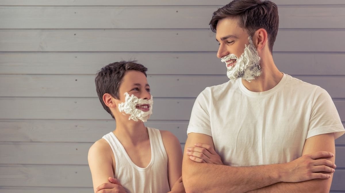 father and young son with shaving cream on their faces