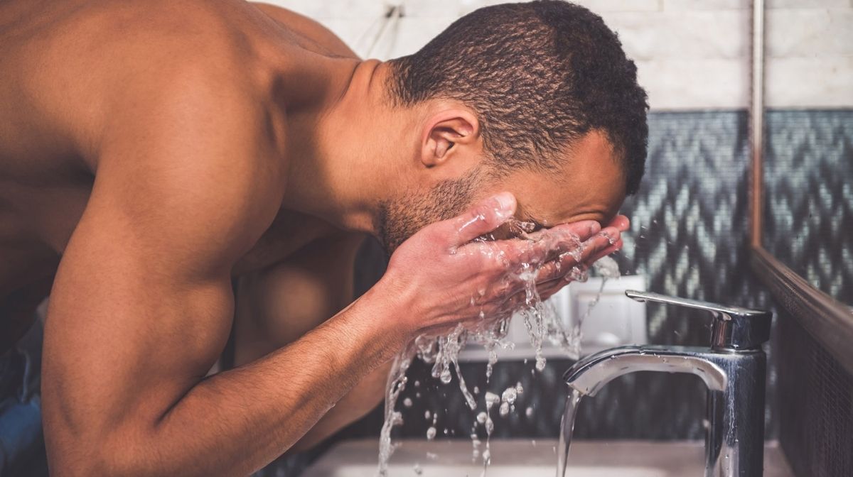 man washing his face at the sink