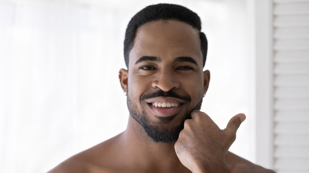A man smiles and feels his skin after beard wash