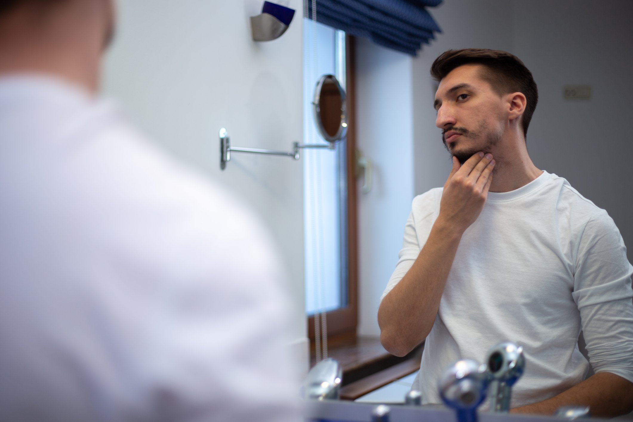 Man feeling patchy beard growth on neck