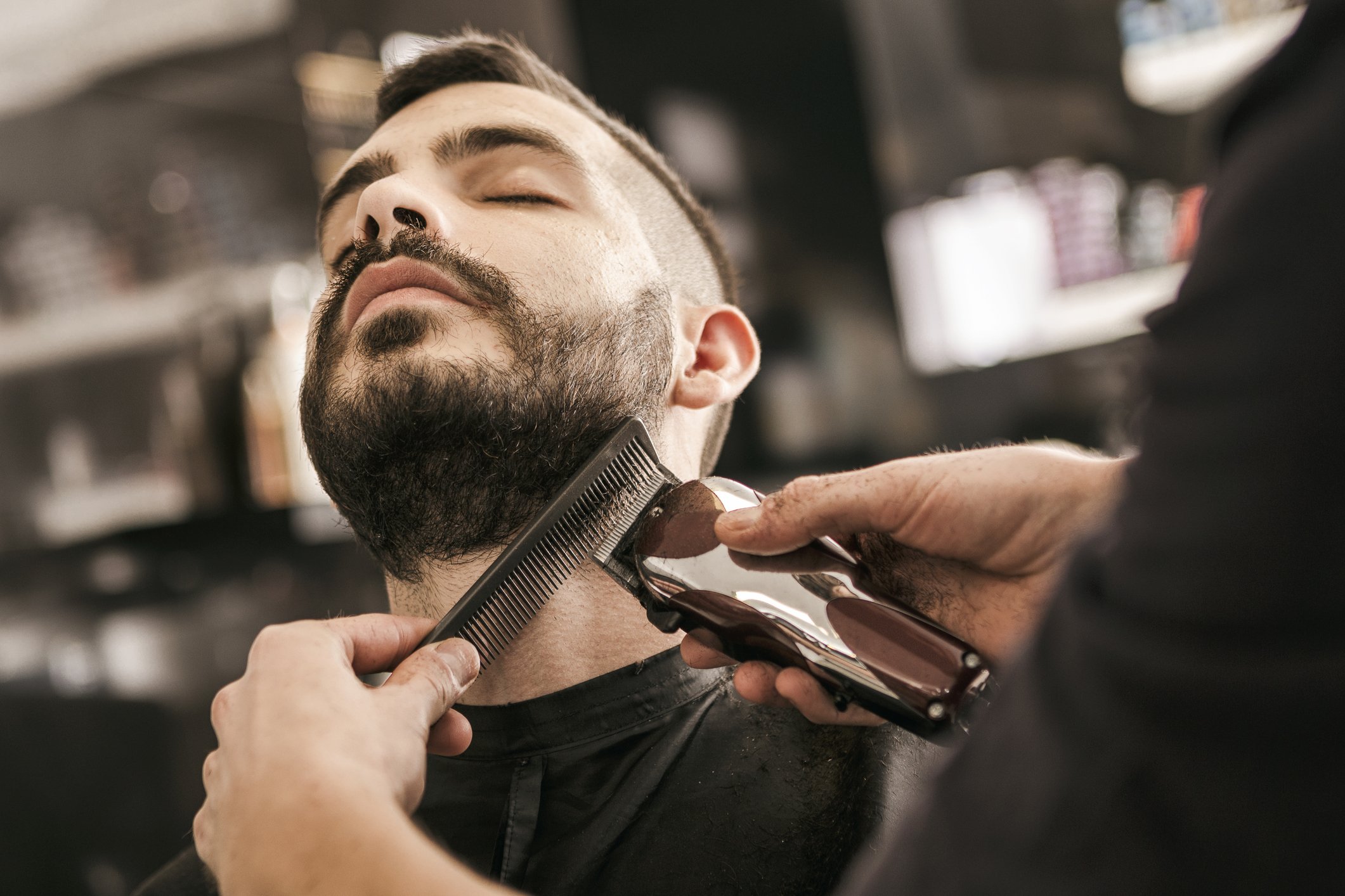 Man getting beard neckline shape up with electric trimmer