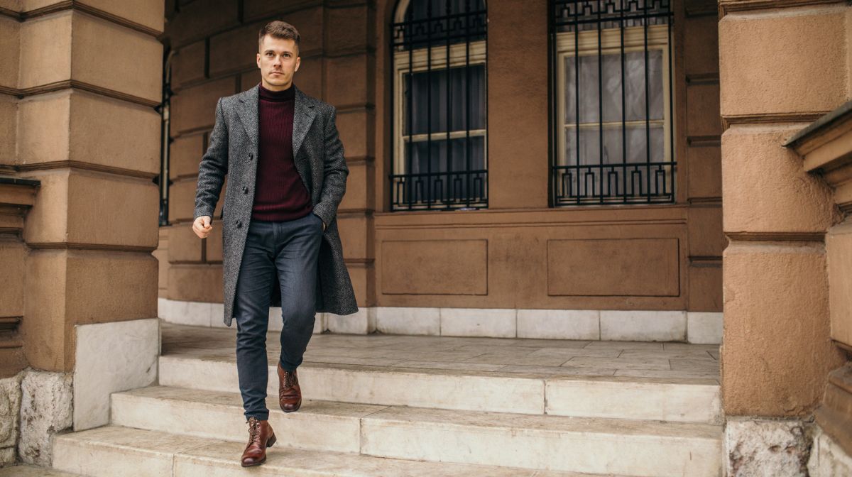 A suave, well-groomed man walks down steps styled in a minimalist wardrobe.